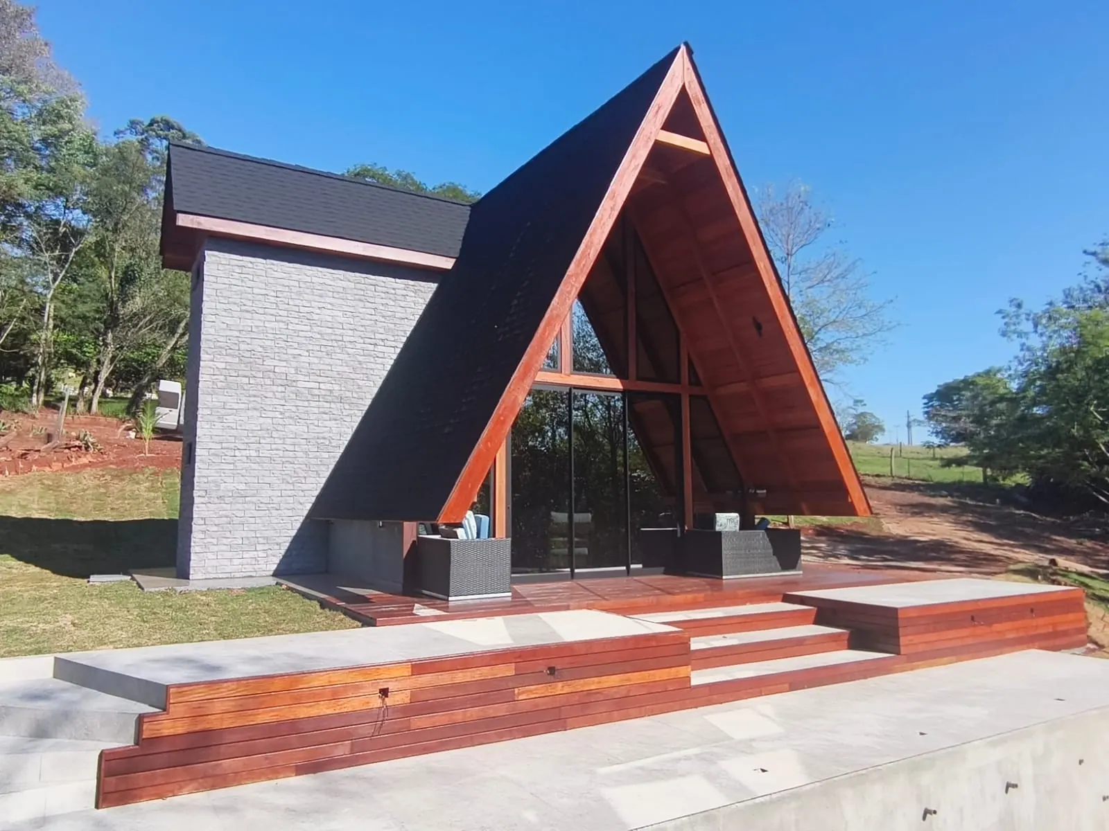 Chalé A-Frame entregue pela Lar Serrano, com deck de madeira e cobertura escura